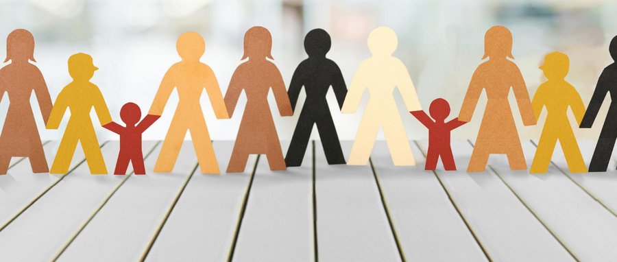 Aus Papier ausgeschnittene Figuren einer Familie auf einem Tisch, die kleine und große Personen darstellen.